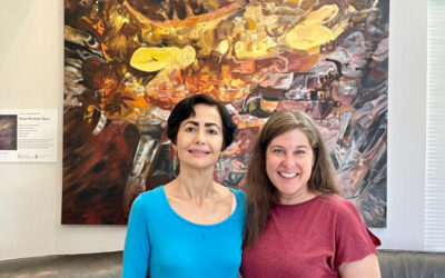 Rubina Anjum and Kathy Sokolic standing in front of one of Rubina's paintings